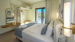 Une chambre d’hôtel avec un lit, une table de chevet, un miroir, une armoire et une fenêtre donnant sur un paysage agréable.