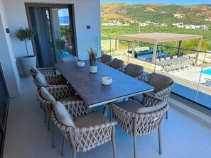 Ein Essbereich mit großem Tisch und Korbstühlen, mit Blick auf eine reizvolle Landschaft.