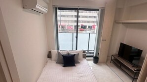 Una habitación de hotel con una cama, un televisor y vistas a la calle.