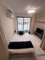 Ein Hotelzimmer mit Bett, Fernseher und Blick auf die Straße.