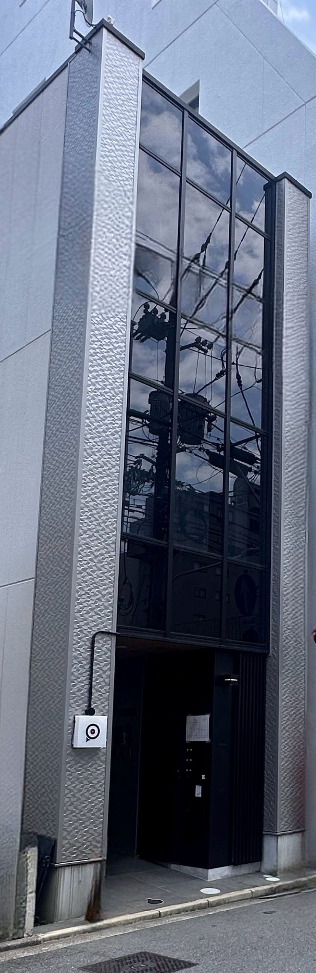 A modern building with a glass facade and a metal textured exterior.