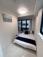 Ein modernes Schlafzimmer mit einem Bett, einer Deckenleuchte, einem Fenster und einem Wandbild.