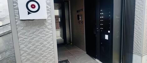 A modern building entrance with a target logo, a wooden ceiling, and a black door.