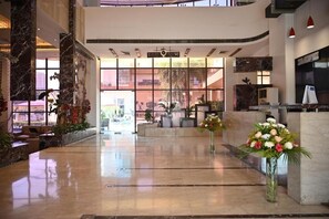 A spacious lobby with a marble floor, a reception desk, and a large window offering a view of the outside. - Club Florence (Gurugram)