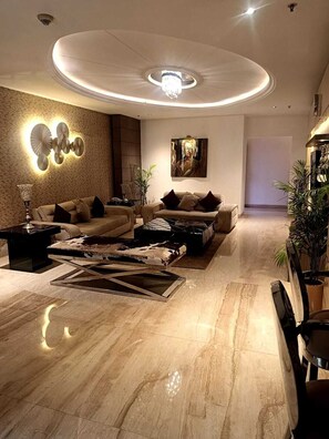 A modern living room with a sofa set, a coffee table, and a wall-mounted light fixture. - Club Florence (Gurugram)