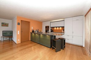 Una cocina moderna con una isla central, armarios blancos y piso de madera.