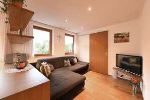 Una sala de estar moderna con sofá, televisor y zona de comedor con frutero.