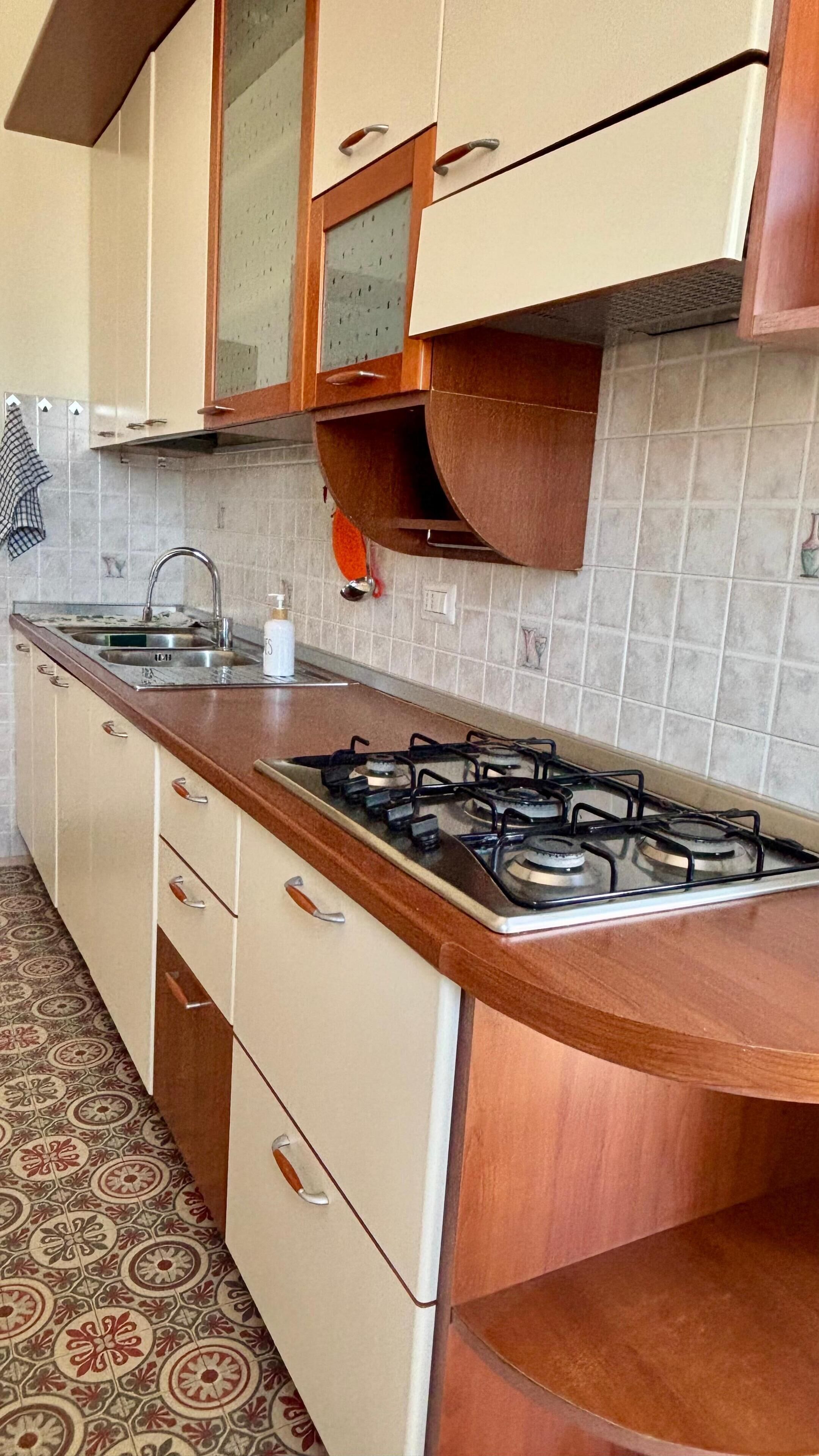 A kitchen with a gas stove, a sink, and cabinets.