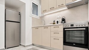 Une cuisine moderne dotée d’un réfrigérateur en acier inoxydable, d’un four encastré, de meubles de couleur beige et d’un sol carrelé en marbre.