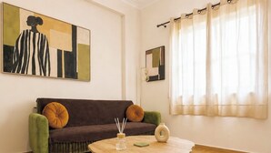 Un salon avec un canapé, une table basse ronde et un tableau accroché au mur.