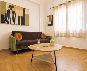 A living room with a sofa, a round coffee table, and a painting on the wall. - The Gkyzi Chapter by MPS (Athina)