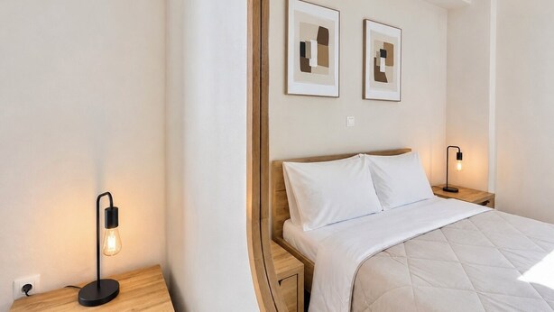 Une chambre à coucher comprenant un lit, deux tables de chevet et deux appliques murales.