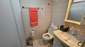 Een badkamer met toilet, wastafel en een handdoekrek met een rode handdoek.