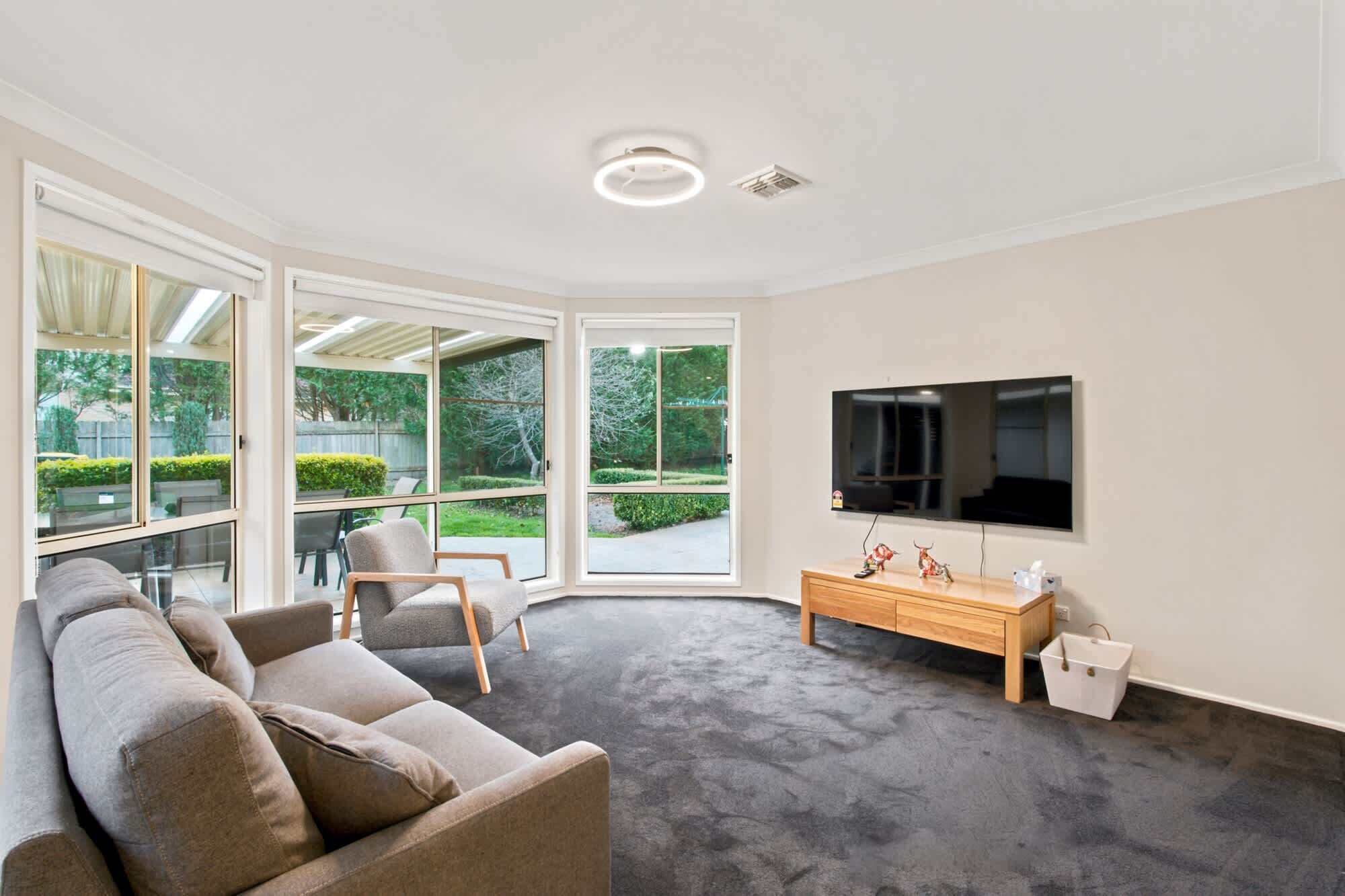 A modern living room with a sofa, a TV, and a wooden cabinet.