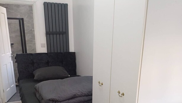 Une chambre à coucher avec un lit, une armoire, un radiateur et une porte.