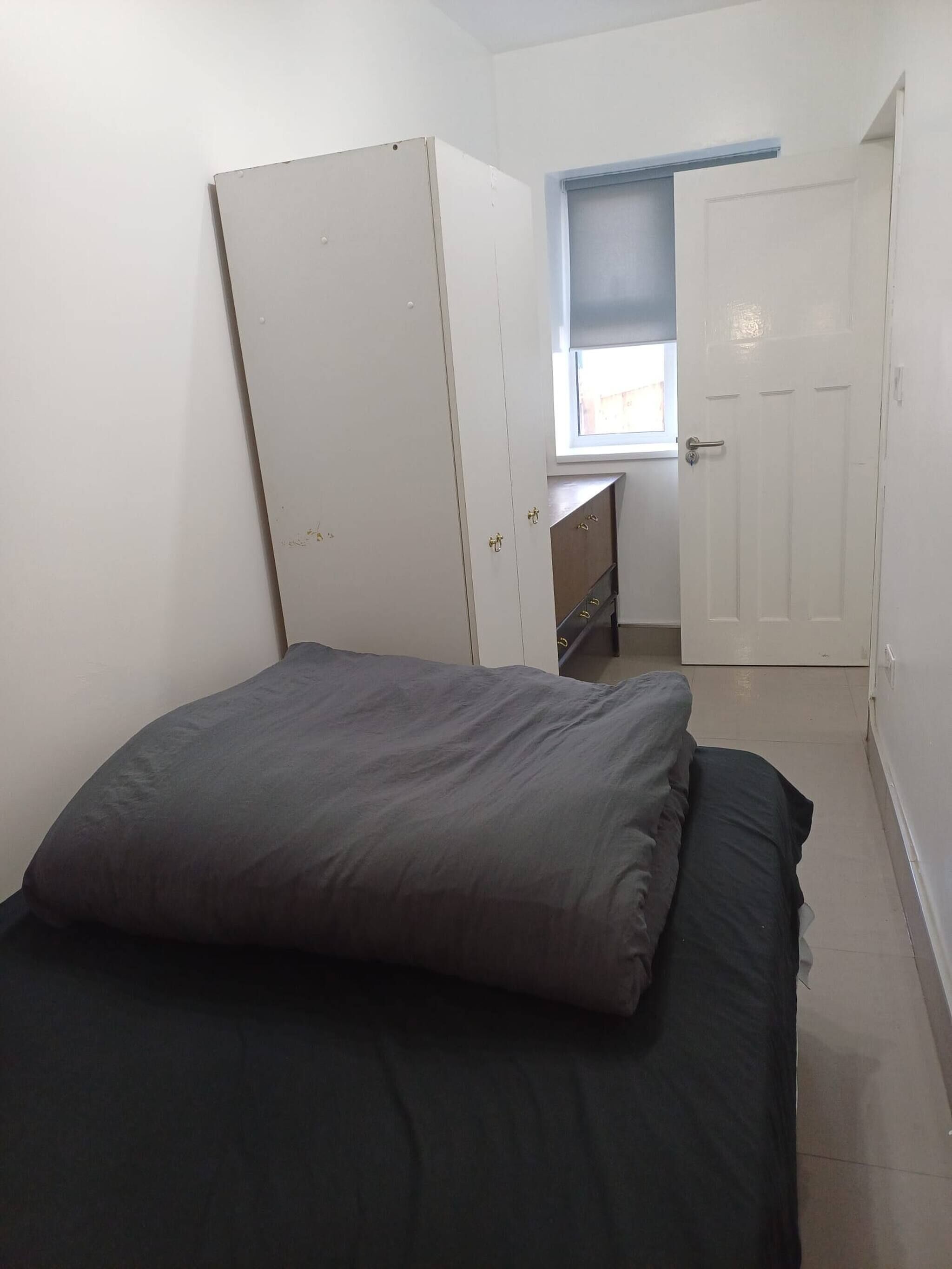 Een slaapkamer met een bed, een kledingkast, een raam en een deur.