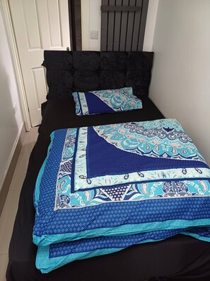 A bedroom with a black headboard, two beds with blue and white patterned bedding, and a white door in the background. - Ensuite Sin Room near CBS Arena and M6 in CV6 4DF (Coventry)