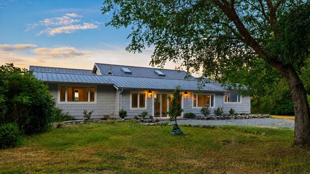 A modern house with a sloped roof, multiple windows, and a well-maintained lawn.