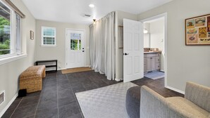 A hallway with a bench, a door, and a view into a kitchen area.