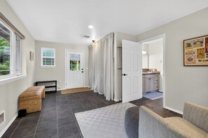 A hallway with a bench, a door, and a view into a kitchen area.