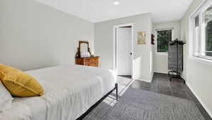 A bedroom with a bed, a dresser, a door, and a window.