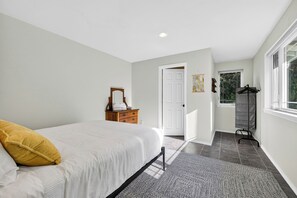 A bedroom with a bed, a dresser, a door, and a window.