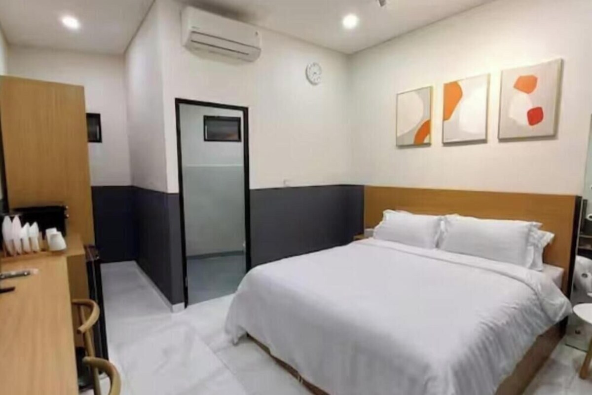 A hotel room with a bed, a desk, a chair, a wardrobe, and a bathroom door.