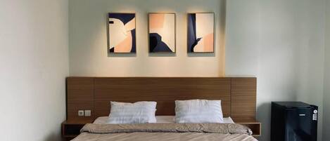 Ein modernes Hotelzimmer mit einem großen Bett, einem Holzkopfteil und drei abstrakten Bildern an der Wand.