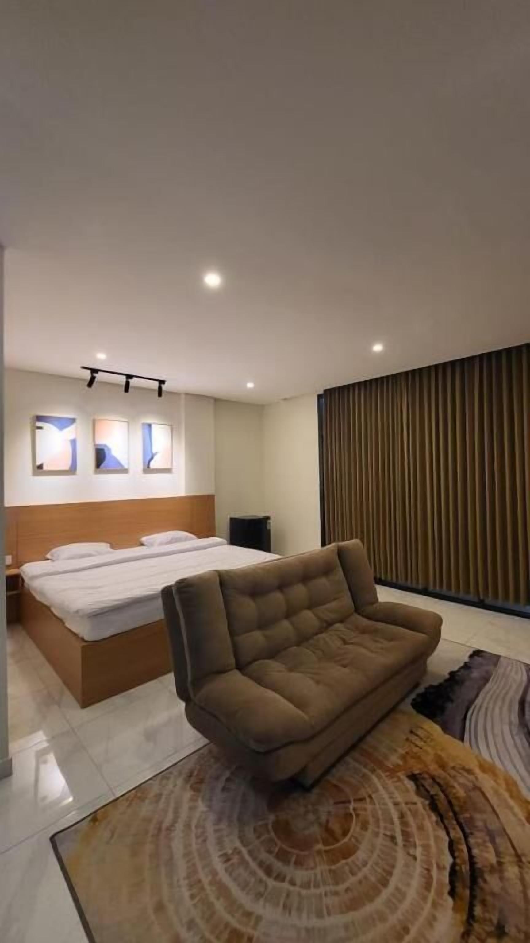 Un dormitorio moderno con cama, sofá y alfombra estampada.
