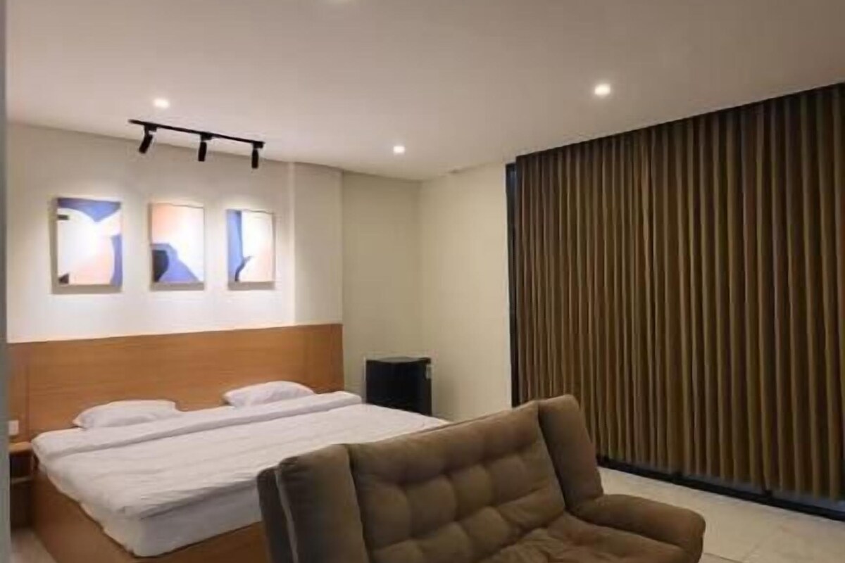 A modern bedroom with a bed, a sofa, and a patterned rug.