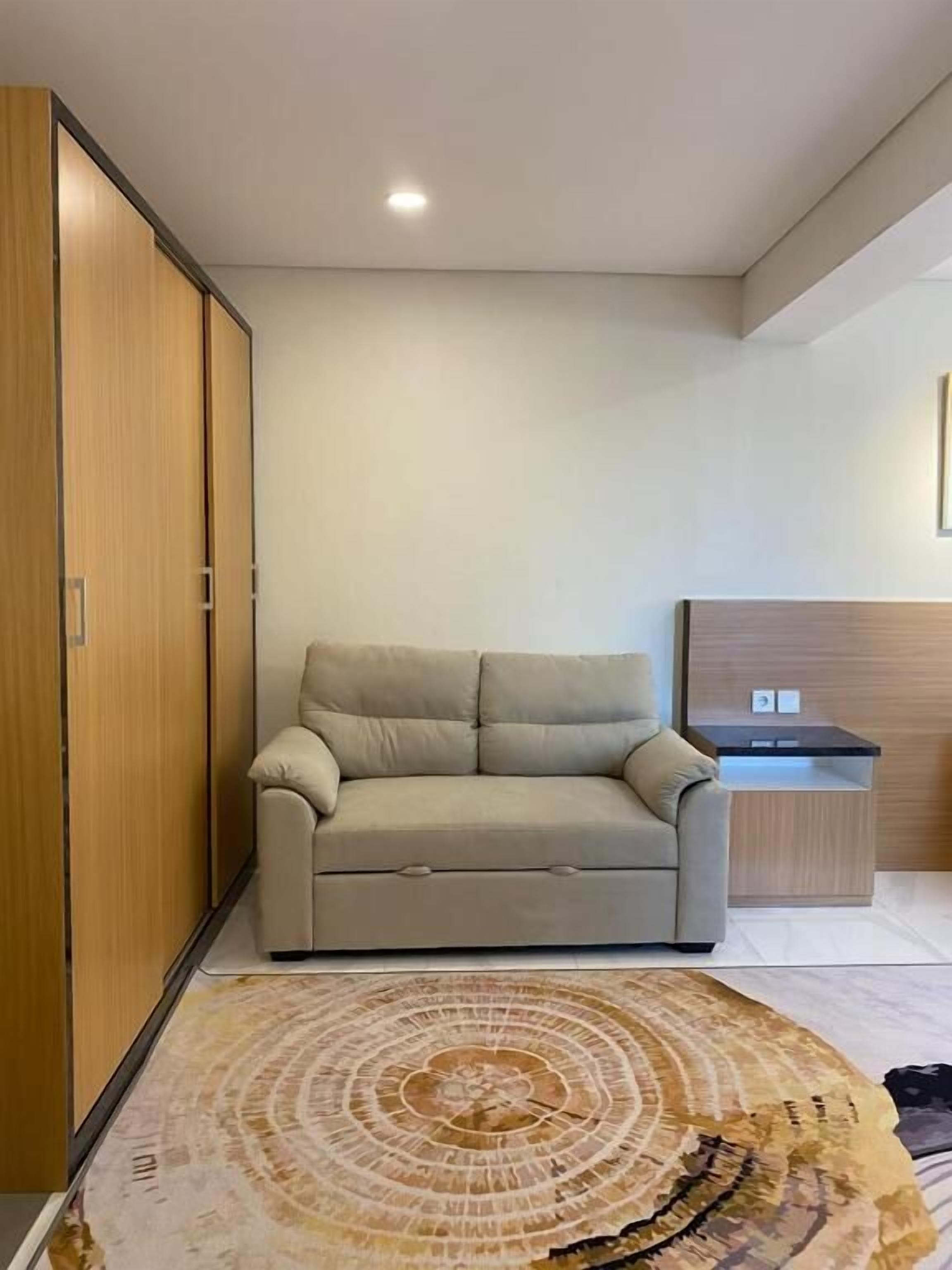 A modern room with a sofa, a wooden wardrobe, and a small desk area.