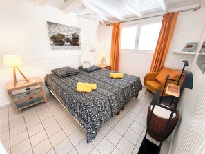 A bedroom with a bed, bedside tables, a chair, and a window with curtains.