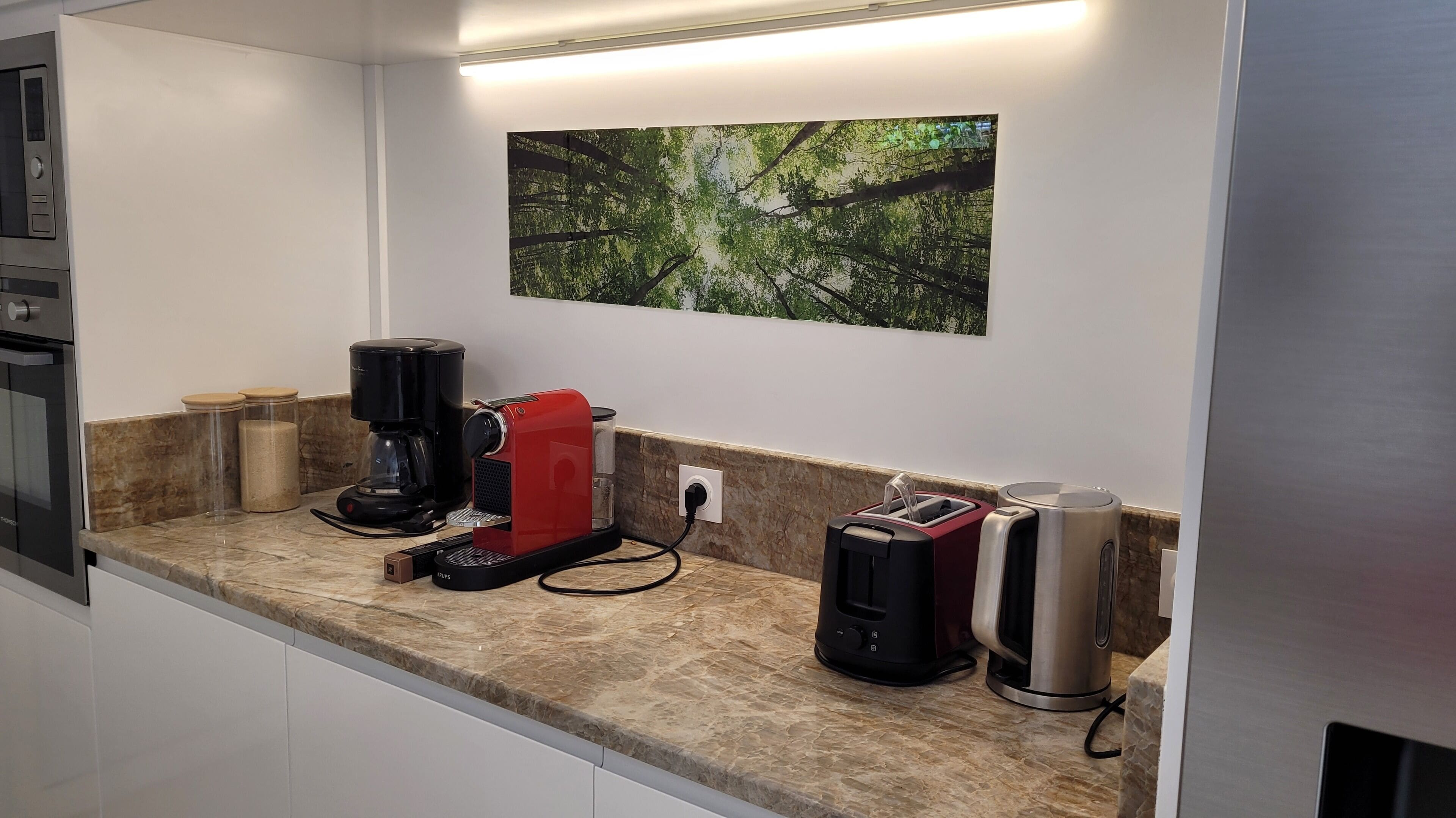 A kitchen with a coffee maker, toaster, and kettle on the counter.
