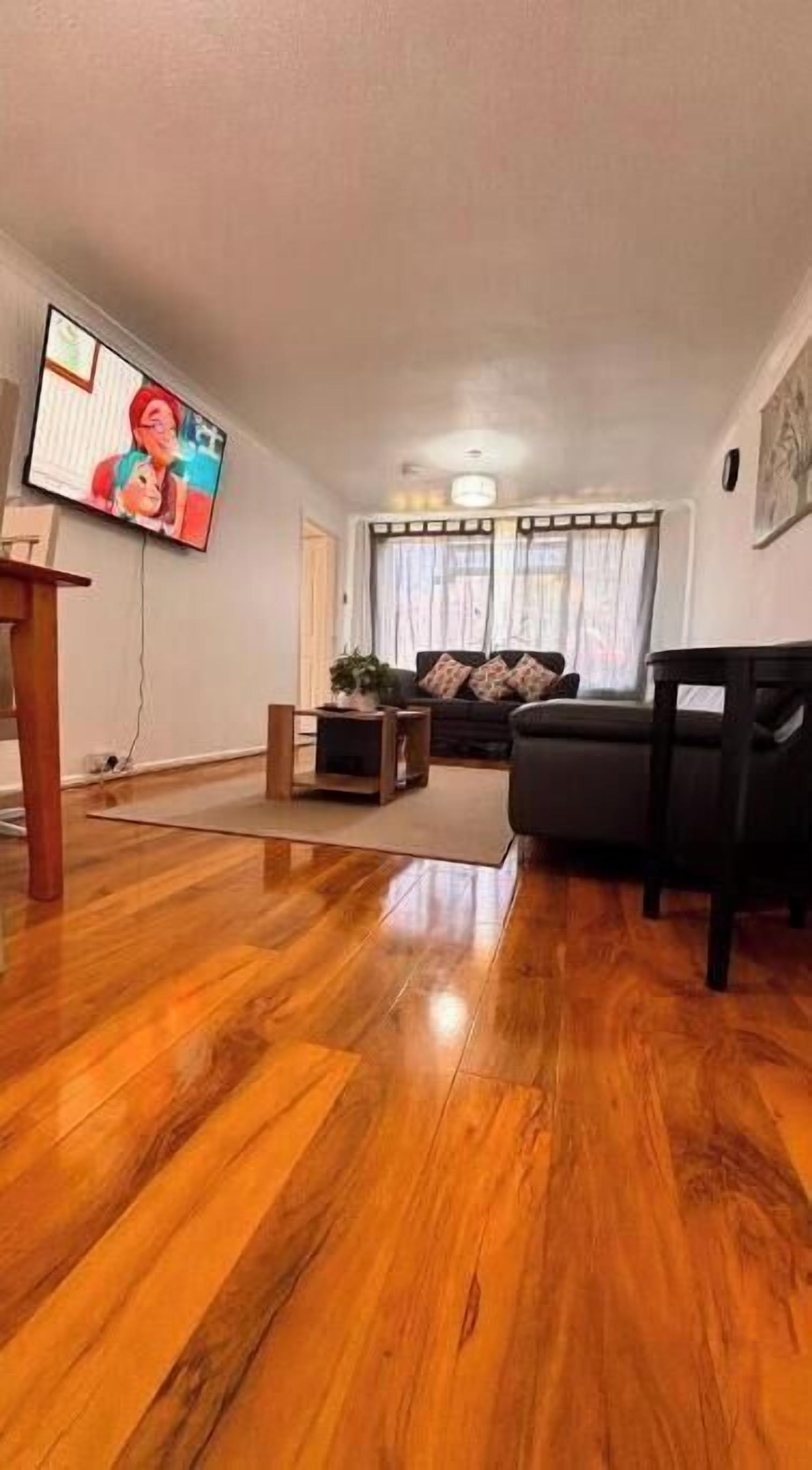 A living room with a wooden floor, a television, a sofa, and a coffee table.