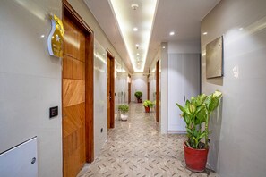 Un pasillo de hotel con puertas de madera, plantas en macetas y piso de baldosas.