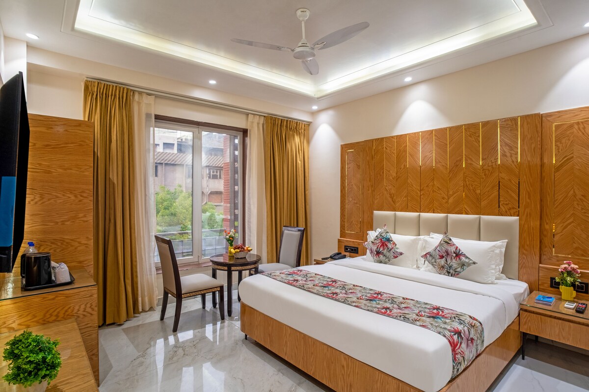 Una habitación de hotel con cama, mesita de noche, silla y una pequeña mesa con una cesta de frutas.