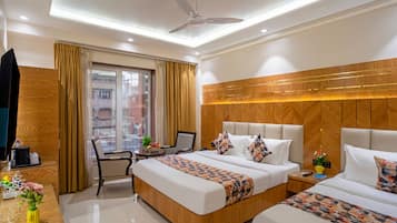 A hotel room with a bed, bedside tables, a desk, a chair, a ceiling fan, and a window with curtains.