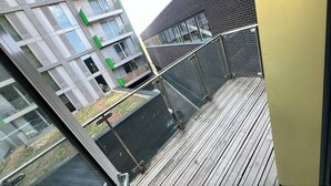 A modern building with balconies, a wooden deck, and a glass railing. - Abbey Nest - 1 Bedroom (London)