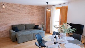 Un salon moderne comprenant un canapé, une table à manger, des chaises et un téléviseur.