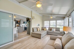 A modern living room with a sofa, a dining area with a kitchen in the background, and a ceiling fan. - Relaxed Resort-Style Living Near Fort Myers Beach (Fort Myers)