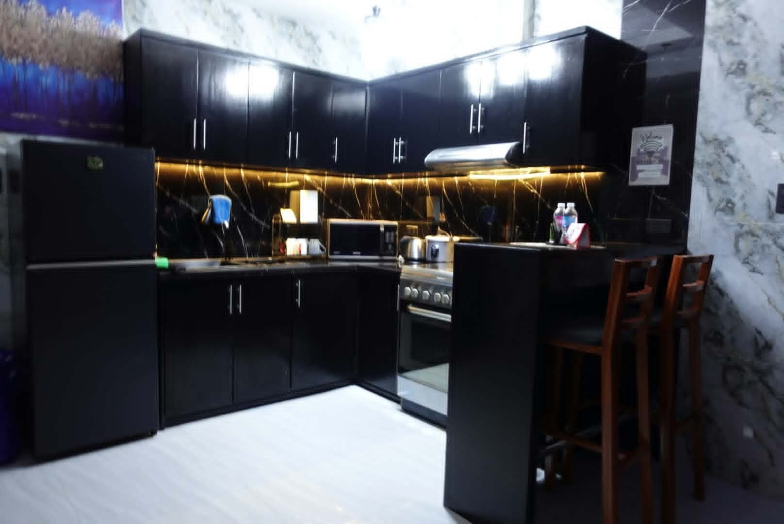 A modern kitchen with black cabinets, a marble backsplash, and a built-in stove.