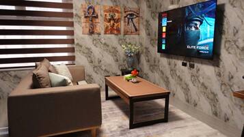 A modern living room with a sofa, coffee table, and wall-mounted TV displaying 'Elite Force'.