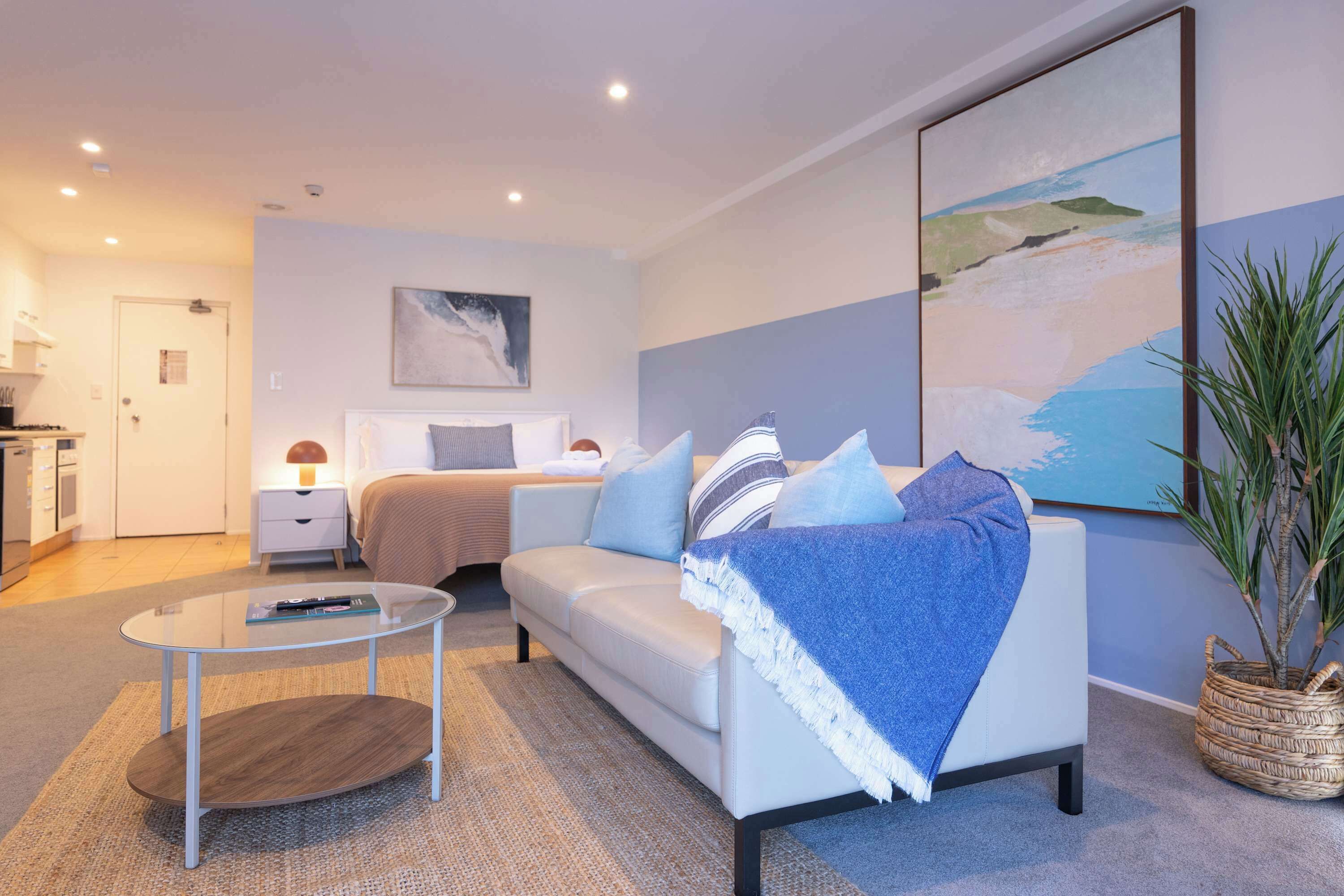 Una moderna camera d'albergo con un letto, un divano, un tavolino da caffè e un quadro appeso al muro.