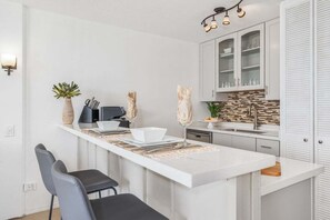 Eine moderne Küche mit Kochinsel, weißen Schränken und einer Spritzschutzwand.
