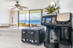 Eine Küche mit Toaster, Kaffeemaschine und Blick auf den Ozean durch ein großes Fenster.