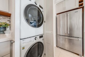 A compact kitchen with a washing machine, a built-in oven, and a stainless steel refrigerator. - Ocean-view 1BR condo with pool, AC and beach access-Maalaea Banyans 112 (Wailuku)