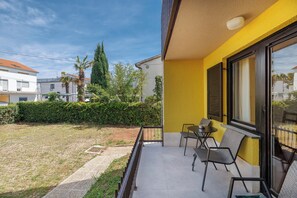 Ein Balkon mit Gartenmöbeln, blauem Himmel und Blick auf angrenzende Gebäude.