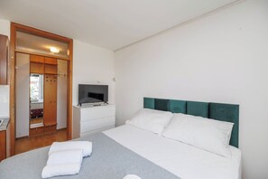 Ein Hotelzimmer mit Bett, Fernseher, Kleiderschrank und angrenzendem Badezimmer.