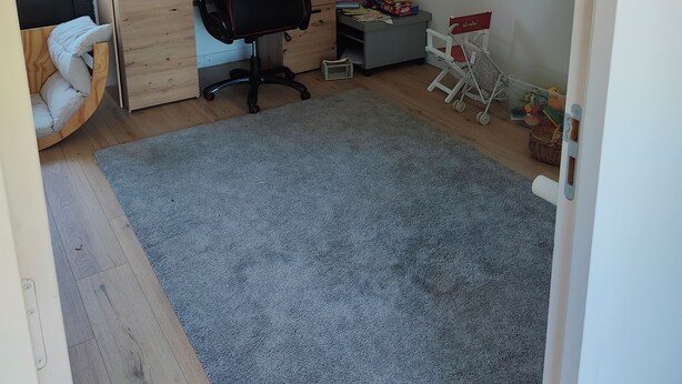 Ein Zimmer mit Schreibtisch, Stuhl, Regalen und einem Fenster.