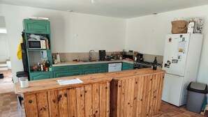 Eine Küche mit einer Holzeile, grünen Schränken, einer Mikrowelle und einem Kühlschrank.